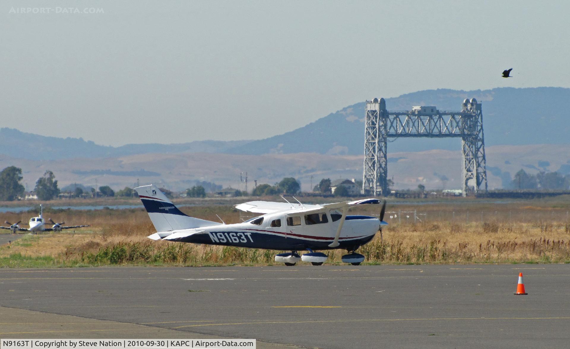 N9163T, Cessna T206H Turbo Stationair C/N T20608975, Brand new Bridgeford FS Cessna T206H taxiing out for takeoff with Napa River RR bridge, hawk and arriving Cessna 421 in background