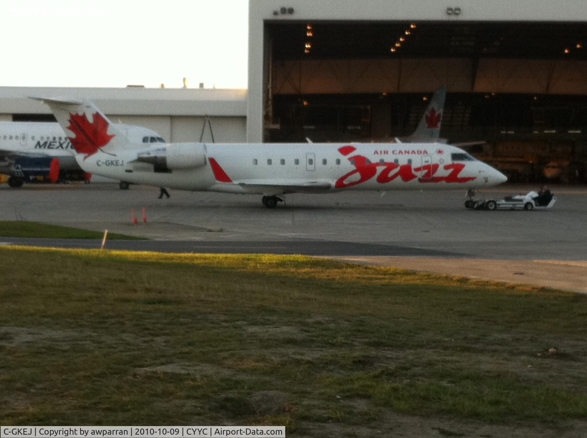 C-GKEJ, 1998 Bombardier CRJ-200ER (CL-600-2B19) C/N 7269, Air Canada Jazz jet getting ready for engine testing.  Never seen this type of tow truck/dolly/whatever before.  The guys are almost lying down on the job.