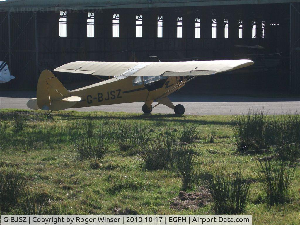 G-BJSZ, 1944 Piper L-4H Grasshopper (J3C-65D) C/N 11874, Through the fence. Classic Piper Cub basking in the morning sun.