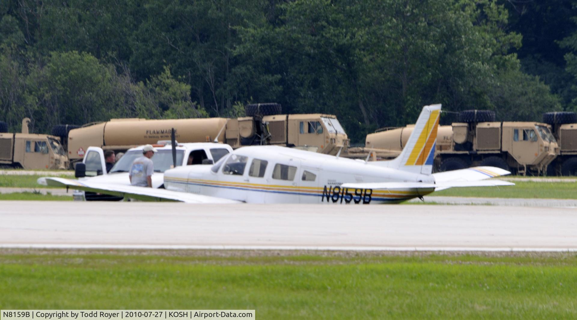N8159B, 1980 Piper PA-32R-301 C/N 32R-8013061, Ran off runway on landing due to damage on port main tire caused by propeller strike from another aircraft while on approach to Oshkosh, other aircraft landed safely.