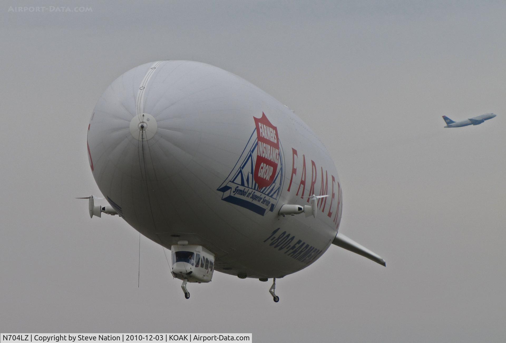 N704LZ, 2008 Zeppelin LZ N07-100 C/N 004, Airship Ventures dirigible in latest color scheme (Farmer's Insurance titles) lifting off from North Field ramp @ Oakland International Airport, CA