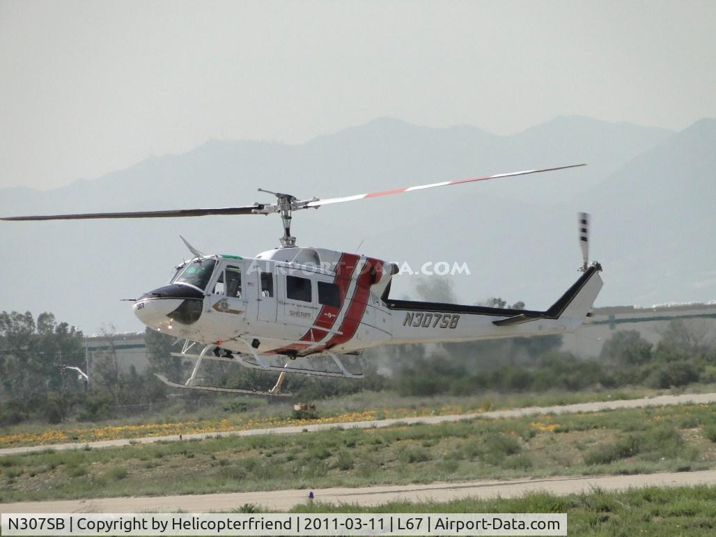 N307SB, 1975 Bell 212 C/N 30781, While ground personnel are attaching the equipment, pilot makes several rear skid only hovers at the taxiway