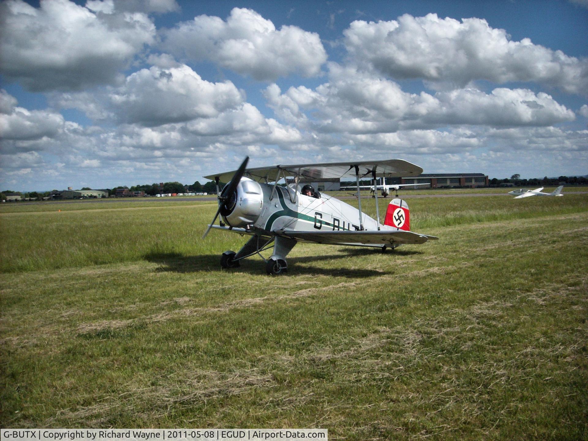 G-BUTX, 1940 Bucker Bu-133C Jungmeister C/N ES.1-4, G-BUTX passes by on grass, Abingdon Air Show 2011