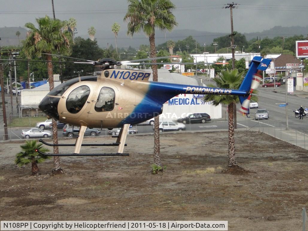 N108PP, 2008 MD Helicopters 369E C/N 0578E, Settling down on the street between tress and Police building