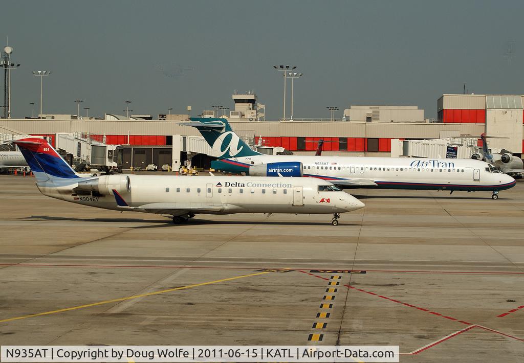 N935AT, 2000 Boeing 717-200 C/N 55069, Delta N904EV advances away from the gates running alongside Air Tran N935AT at Atlanta.