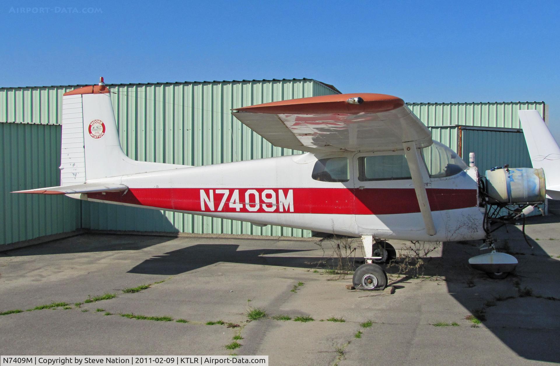 N7409M, 1959 Cessna 175 Skylark C/N 55709, Looking rather forlorn ex-Moore Aviation (tail logo) straight tail 1959 Cessna 175 minus engine and sporting blue oil drum instead @ Tulare, CA