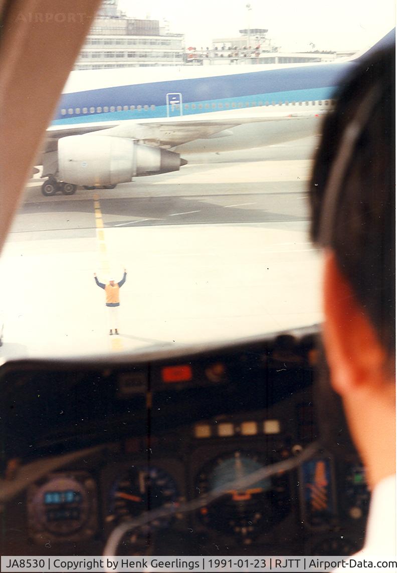 JA8530, 1975 Douglas DC-10-40F C/N 46920, Japan Air Lines.View from  the cockpit. Marshaller at work. Arrival from Kagoshima , Haneda airport.ANA B747 is leaving.