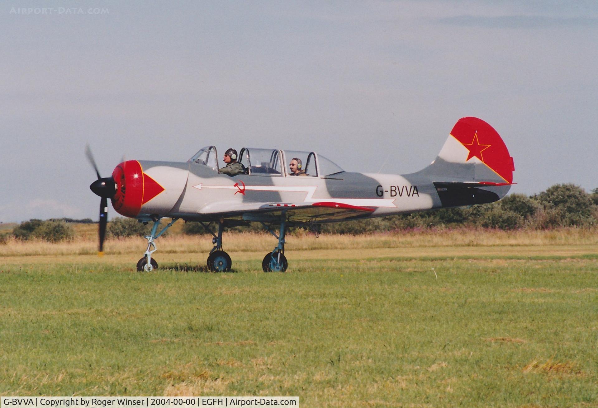 G-BVVA, 1987 Bacau Yak-52 C/N 877610, Returning to base after formation aerobatics practice. Wearing a newly applied dark grey/pale grey camouflage scheme. Circa July/August 2004.
