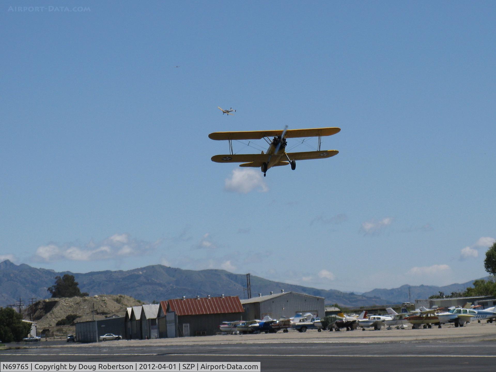 N69765, 1941 Boeing A75N1 (PT17) C/N 75-1044, 1941 Boeing Stearman A75N1 as Navy N2S1, Continental W670-5 220 Hp, takeoff climb Rwy 22 with N99711 Ercoupe above and far behind turning final