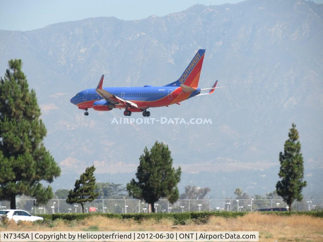 N734SA, 1999 Boeing 737-7H4 C/N 27866, Over the trees and outer fence for 26R