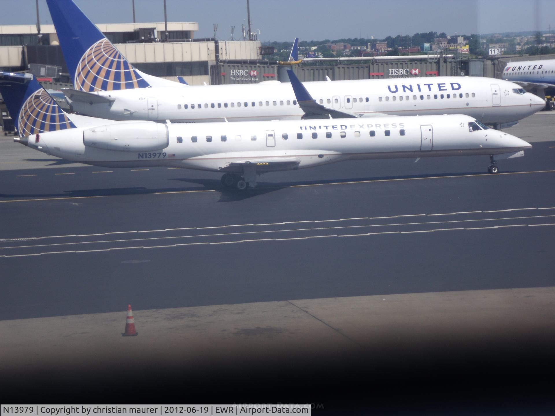 N13979, 1999 Embraer ERJ-145LR (EMB-145LR) C/N 145181, erj-145lr next to a 737-800 staring up it's engins