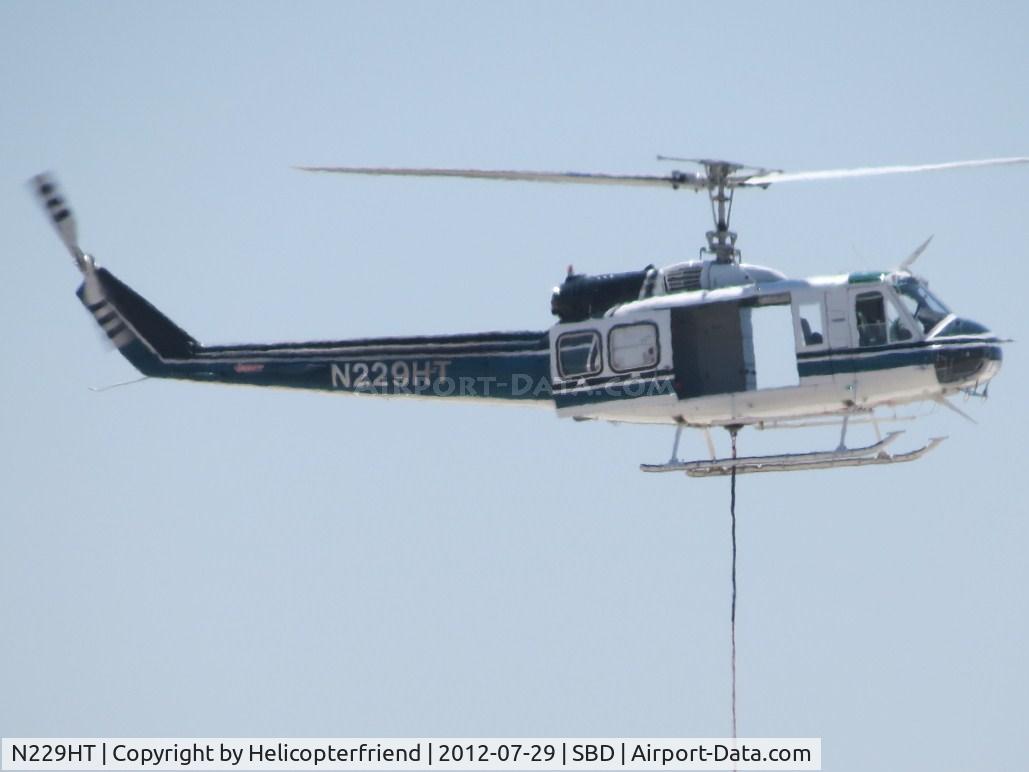N229HT, 1980 Bell 205A-1 C/N 30330, Power on and holding cable steady & tight, moving equipment off of & onto roofs south of the airport