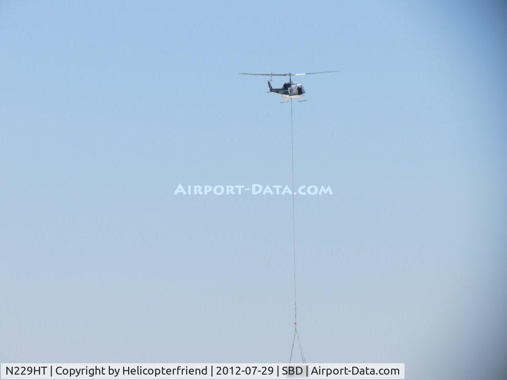 N229HT, 1980 Bell 205A-1 C/N 30330, Power on and holding cable steady & tight, moving equipment off of & onto roofs south of the airport