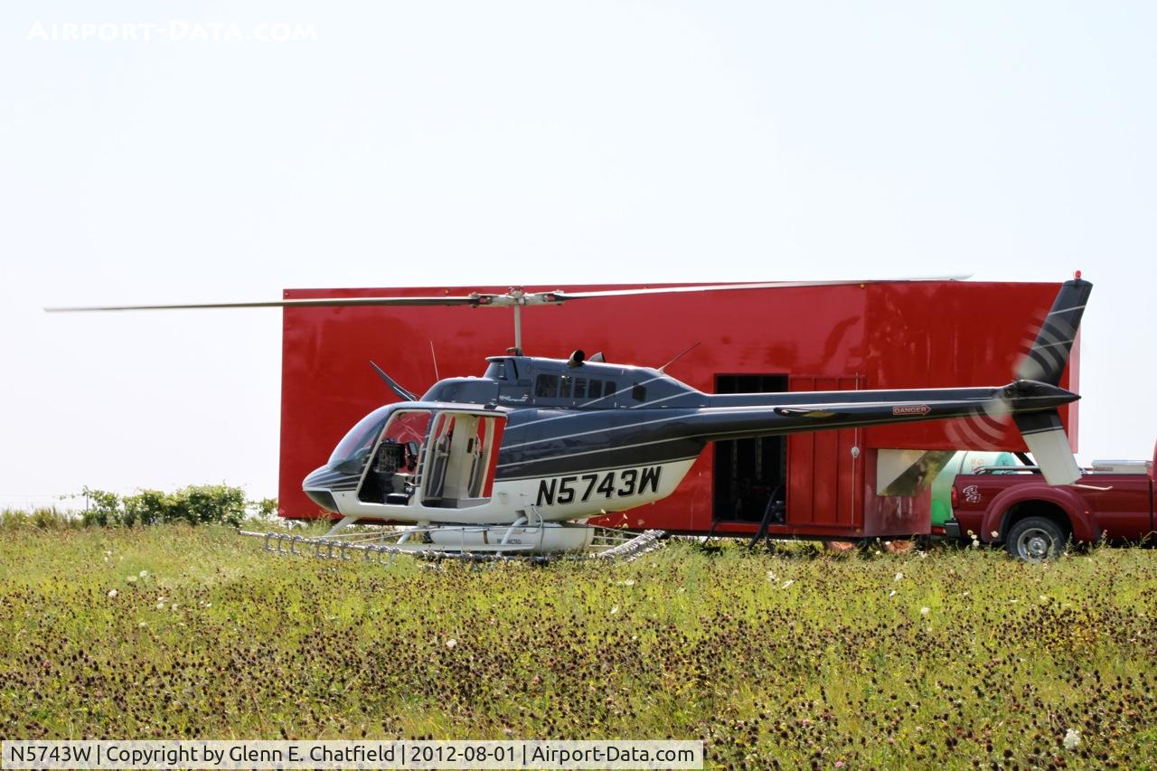 N5743W, 1980 Bell 206B C/N 3050, Taking on another load for crop dusting.  At the SE corner of county routes W38 and A38, about six miles NE of Decorah, IA