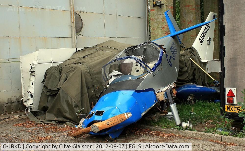 G-JRKD, 1995 Jodel D-18 C/N W177, The wreck of the Airvan (G-CDYA) is under the canvas and the wings of it are propped-up against the hangar.
If you look to the left of the trailer, you'll see the remains of a dark-blue giro-copter.