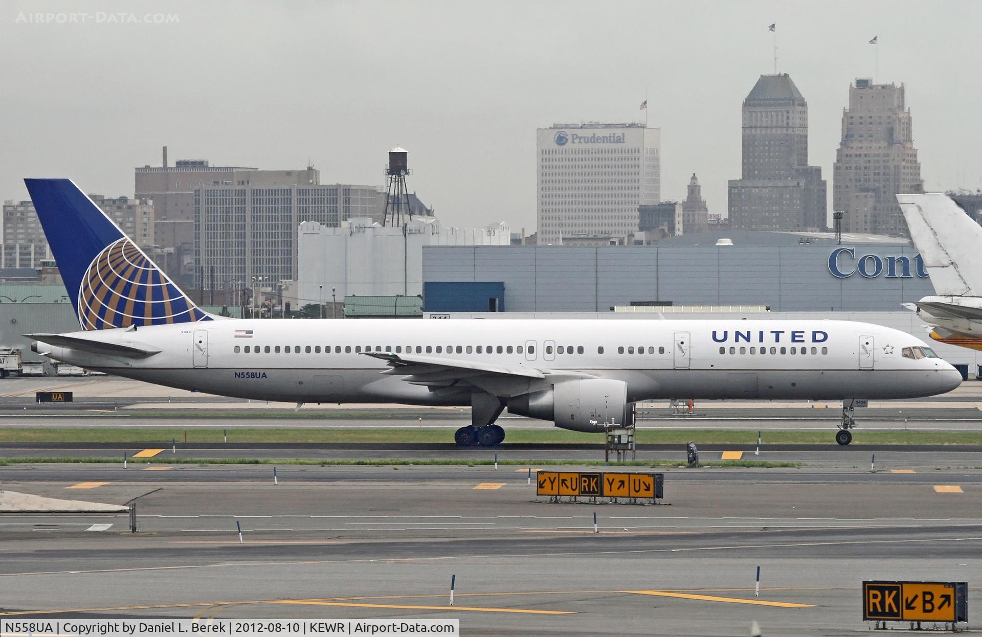 N558UA, 1992 Boeing 757-222 C/N 26654, An impressive Boeing 757 passes one of the cargo terminals at Newark Aiport; the Newark city skyline offers a picturesque backdrop.