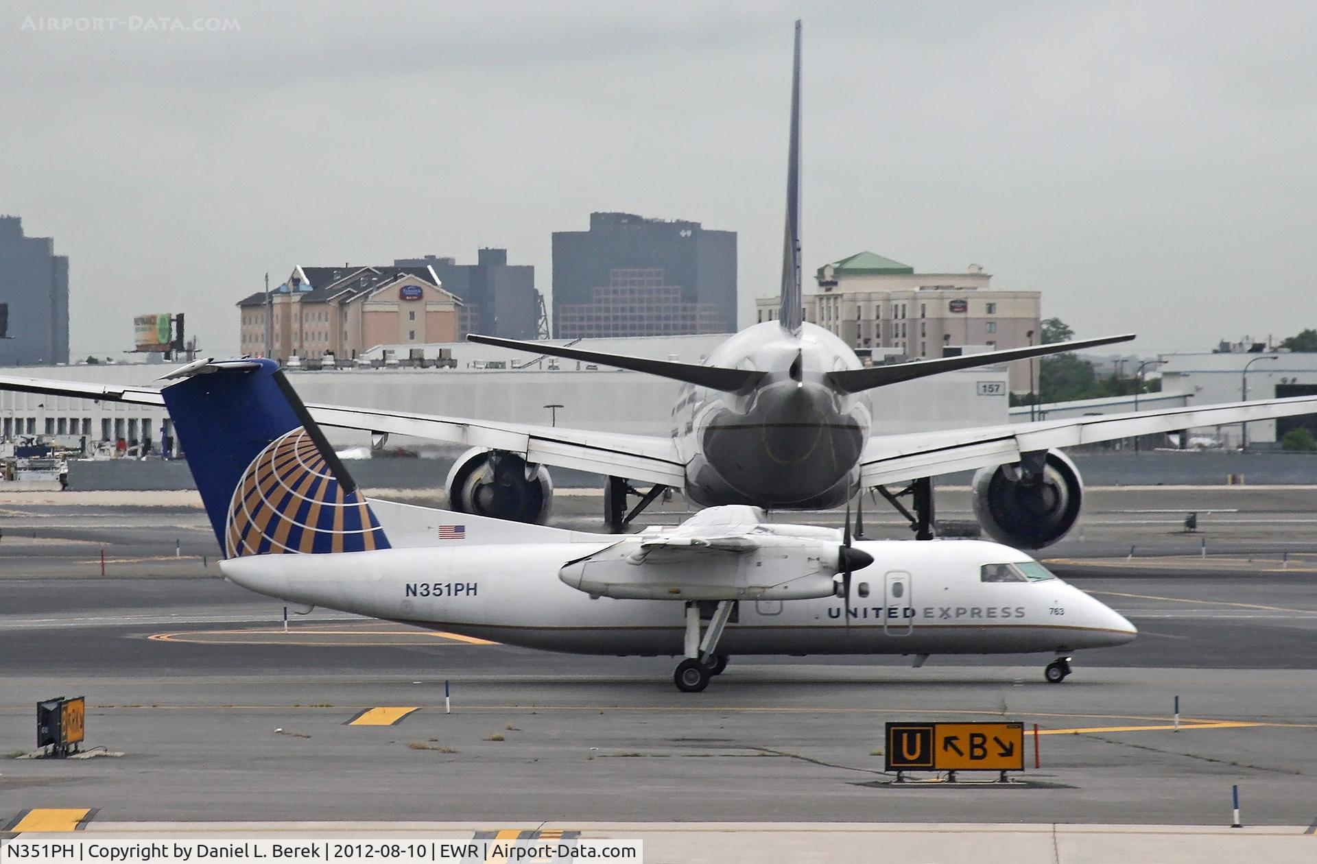 N351PH, 1997 De Havilland Canada DHC-8-202 Dash 8 C/N 490, Strolling behind a United Triple-7, this Dash-8 shows off the amazing difference in size between these two aircraft.