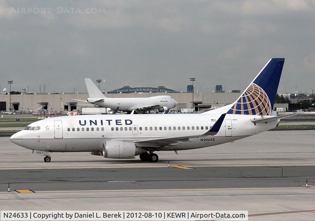 N24633, 1995 Boeing 737-524 C/N 27901, A United Boeing 737-524 (built 1995) taxies past Newark's terminal C, while a 747 in the background maintains an air of indifference.