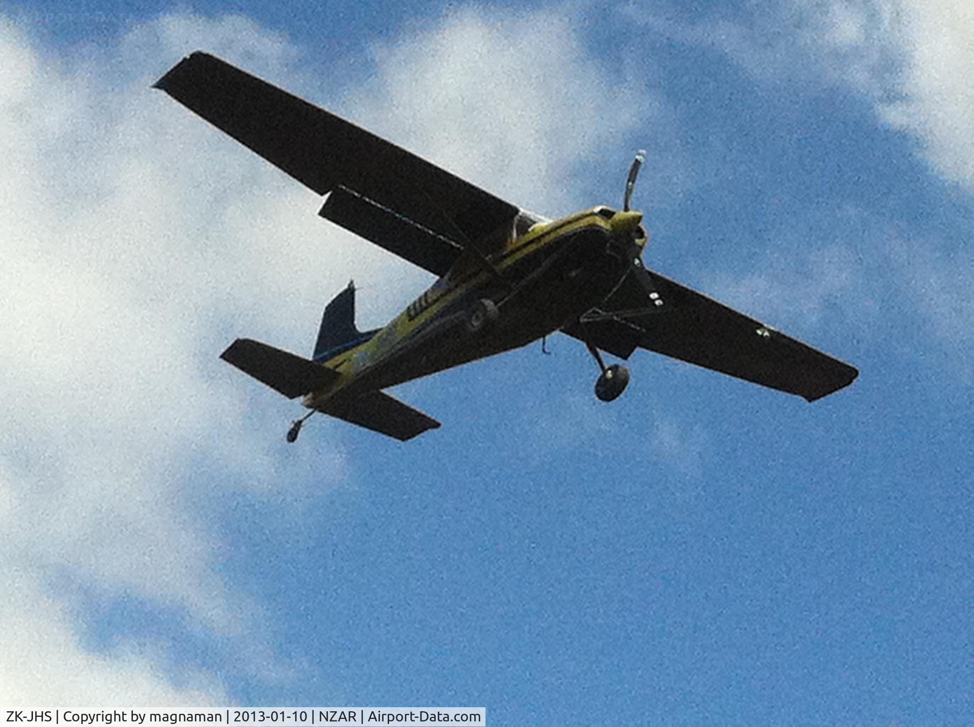 ZK-JHS, Cessna 185C Skywagon C/N 185-0677, A dark colour scheme not helped by bright sun - but good angle as it lands over where I was parked.