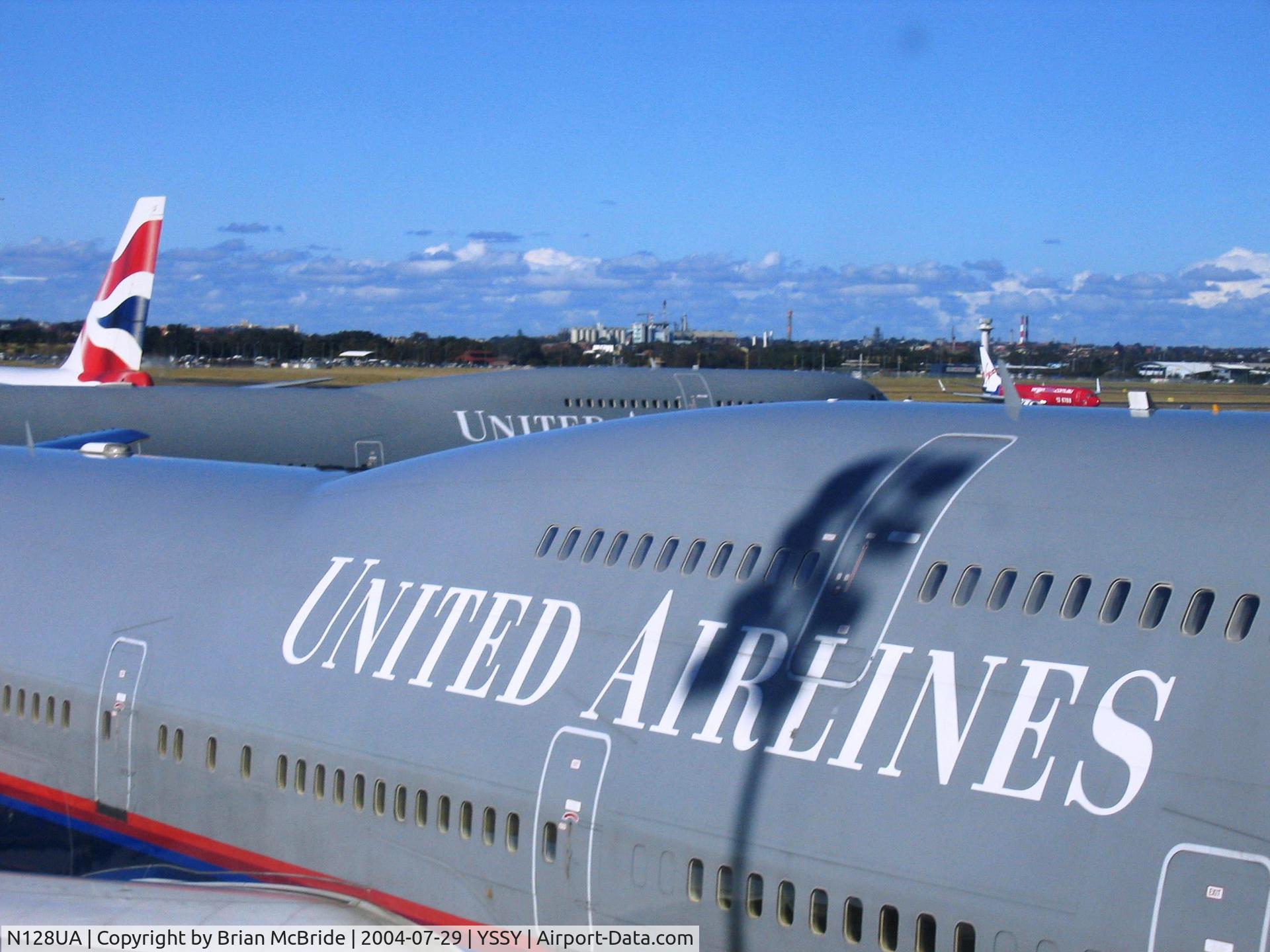 N128UA, 2000 Boeing 747-422 C/N 30023, United Airlines. 747-422. N128UA 8128 cn 30023 1245. Sister 744 Ship N105UA behind her. Sydney - Kingsford Smith International (Mascot) (SYD YSSY). Image © Brian McBride. 29 July 2004