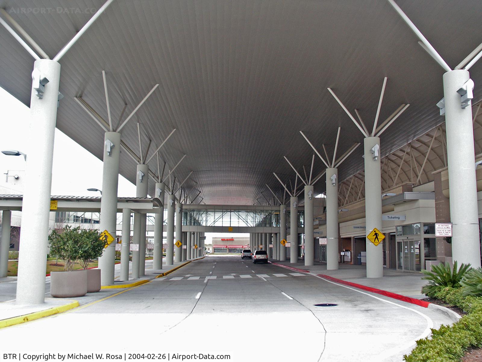 Baton Rouge Metropolitan, Ryan Field Airport (BTR) - The BTR terminal drop-off/pickup area. The ternimal is to the right the parkinlot is to the left. Right in front al the way in the back is the rental cars offices area. This arc roof helps to keep away the beating sun in the summer.