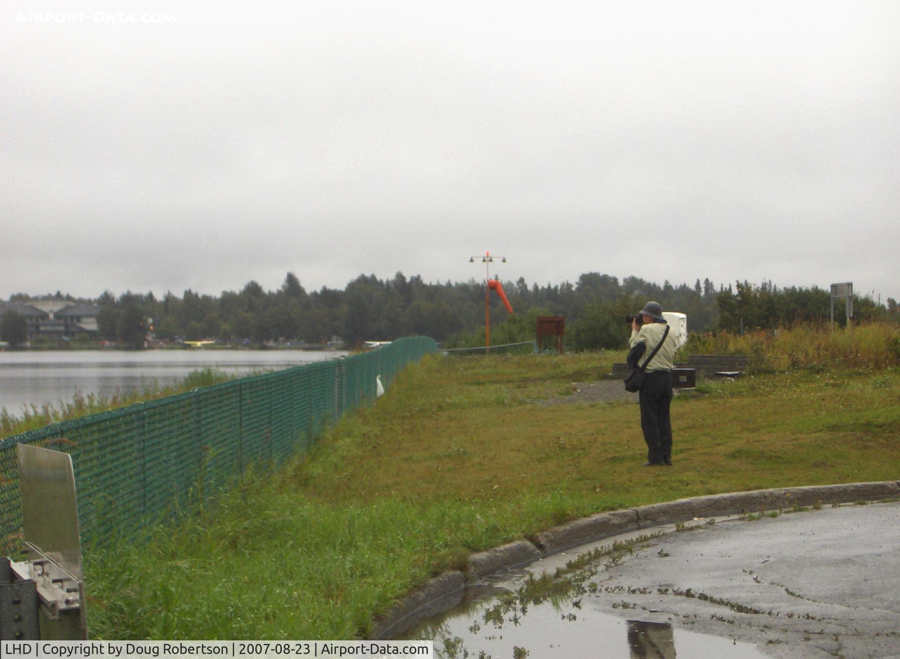 Lake Hood Seaplane Base (LHD) - Japanese Bus Tour-Seaplane viewing and photography on a wet, but flyable day. Tourist getting one last shot.