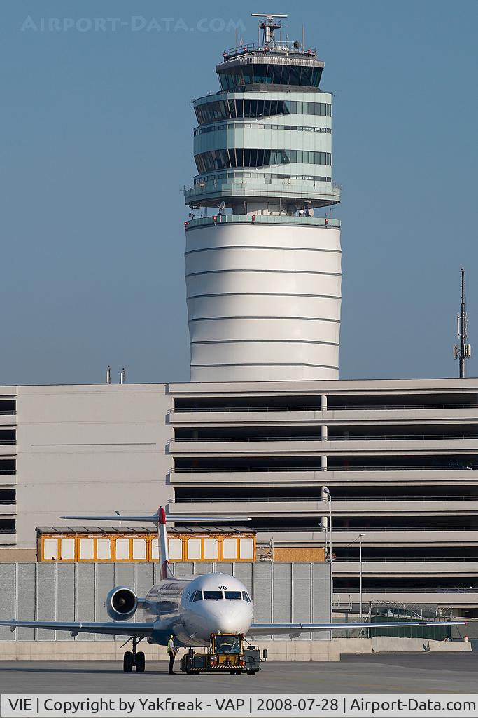 Vienna International Airport, Vienna Austria (VIE) - Fokker 100 pushing back in front of ATC tower
