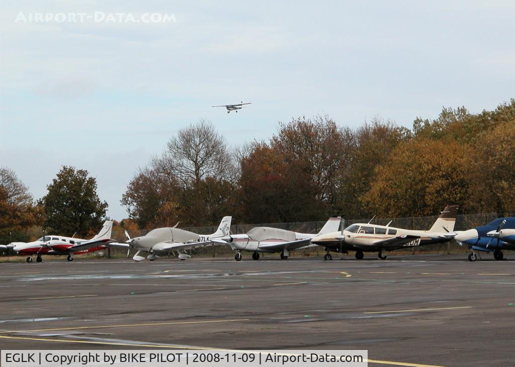 Blackbushe Airport, Camberley, England United Kingdom (EGLK) - AIRCRAFT PARKED OUTSIDE MAIN TERMINAL. AIRCRAFT ABOVE TREES APPROACHING RUNWAY 25