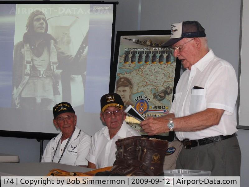 Grimes Field Airport (I74) - Veterans Seminar.  Beyond speaker Art Kemp are a poster dedicated to Art and a photo of him right after he shot down 2 German fighters.