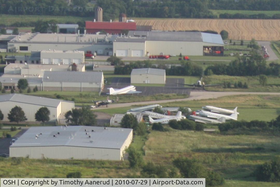 Wittman Regional Airport (OSH) - While departing Airventure on Runway 36 I was taking pictures of the Oshkosh truck inventory.  On a closer look of my photos I spotted Basler Turboprop Conversions facility. There's a B-25 in this photo too.