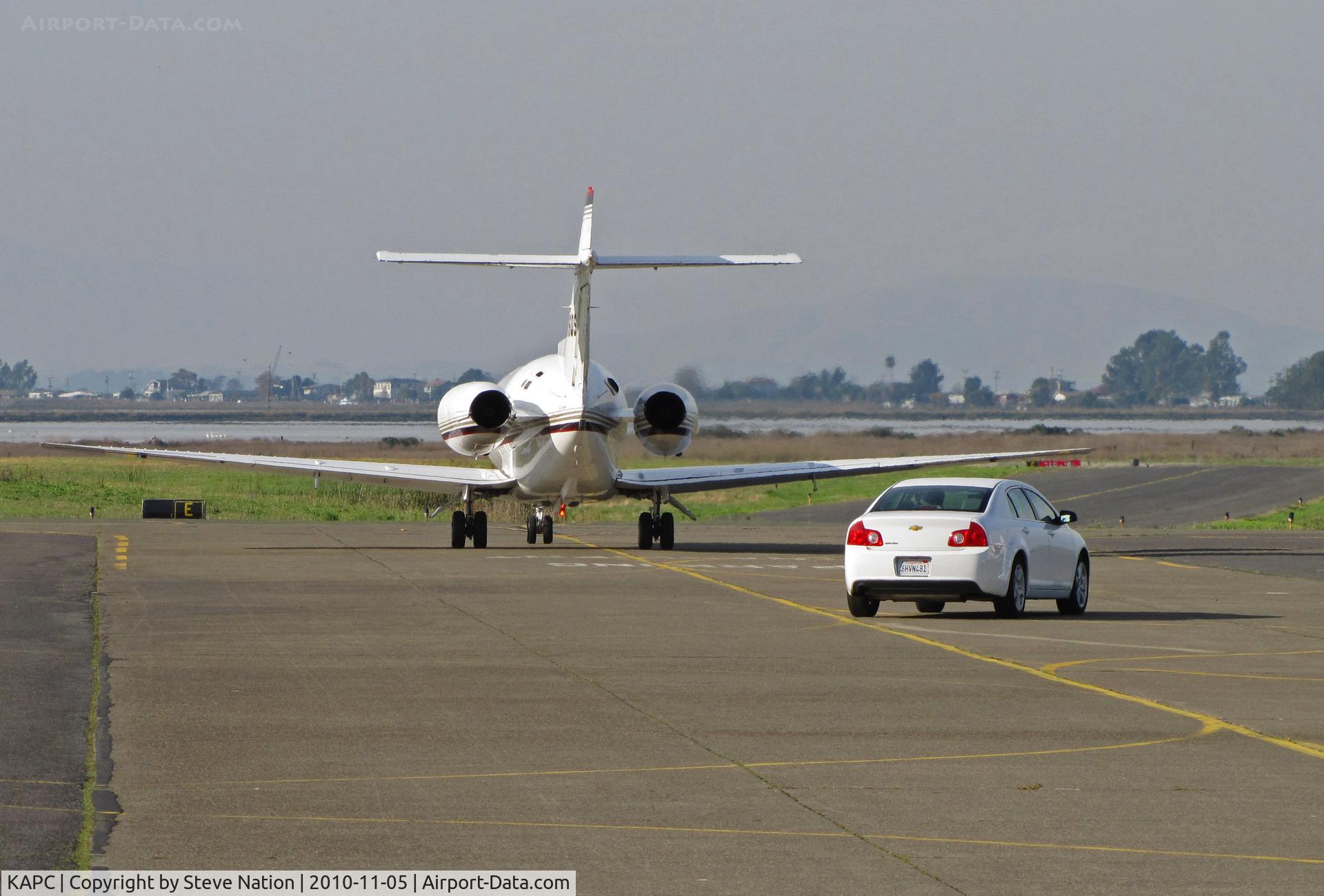 Napa County Airport (APC) - Planes and Cars share taxiway - NetJets Hawker 800XP N886QS departing for KMHR/Mather Field, Sacramento, CA with Chevy in trail