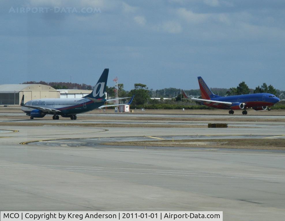 Orlando International Airport (MCO) - Southwest 737 landing as an AirTran 737 taxis for departure.