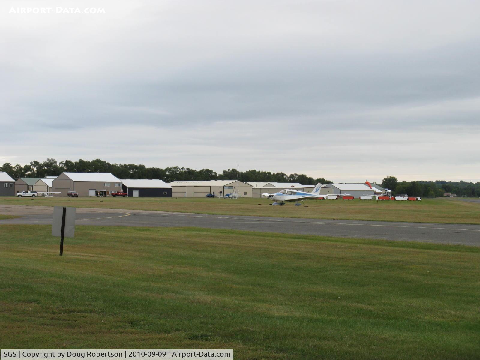 South St Paul Muni-richard E Fleming Fld Airport (SGS) - Aircraft hangars, windsock, taxiway in foreground