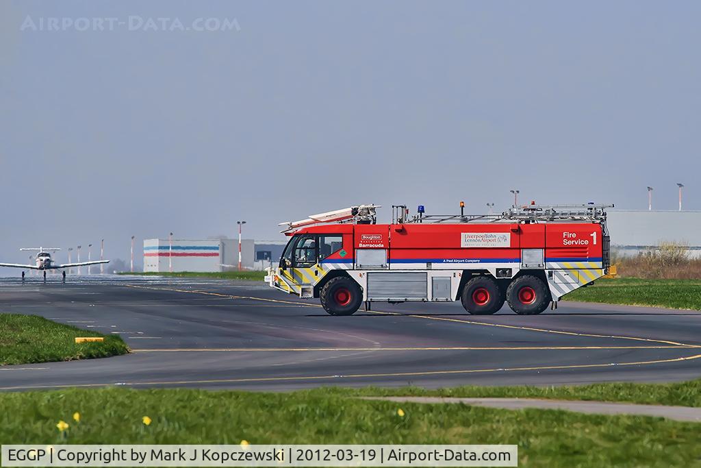 Liverpool John Lennon Airport, Liverpool, England United Kingdom (EGGP) - Liverpool Fire Service tender 1 on taxiway with light aircraft and airport terminal building in background.  