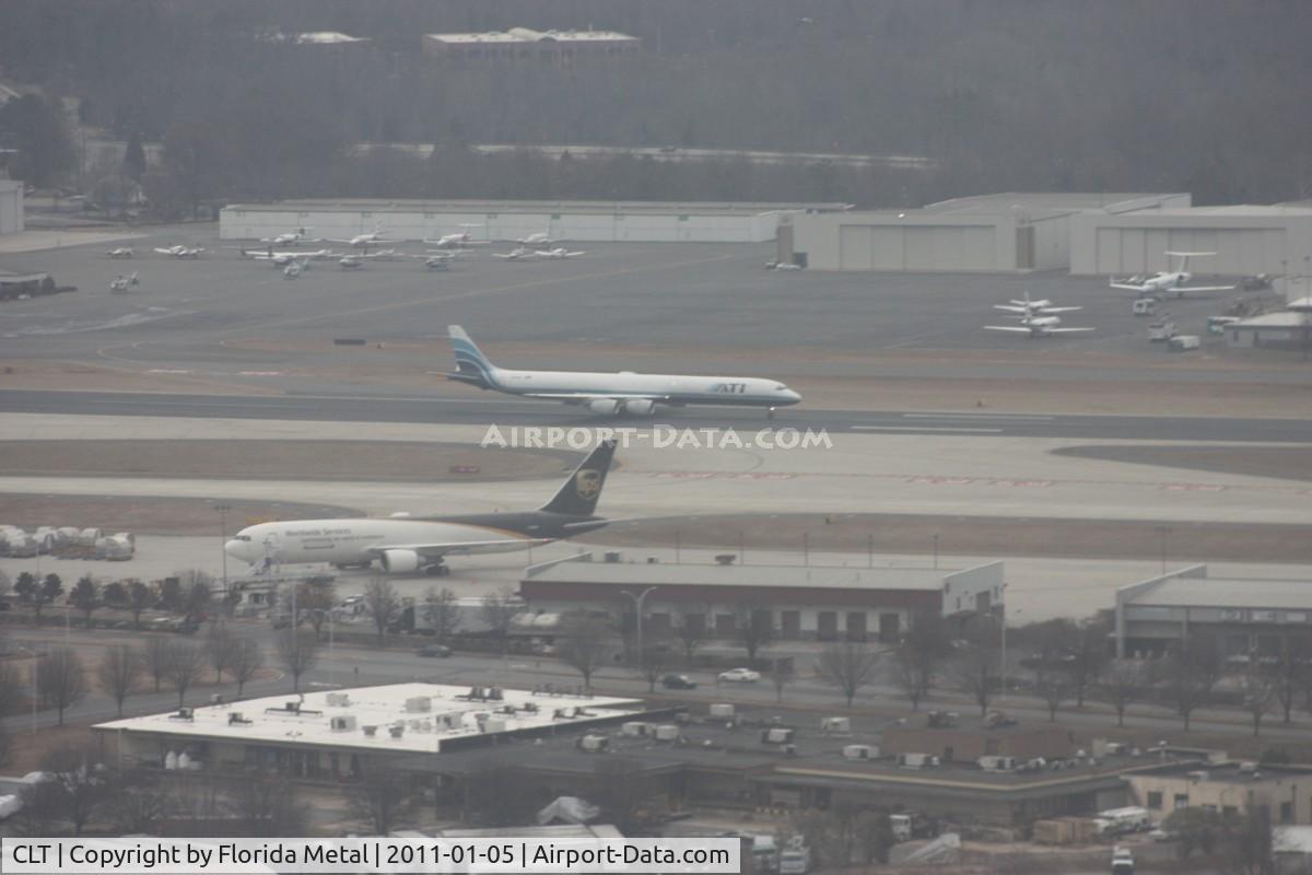 Charlotte/douglas International Airport (CLT) - Not top quality - it is cloudy and hazy, we are moving and the windows were scratched on my plane N744P (US A319 Piedmont colors).  ATI DC-8 lands on parallel runway, UPS 767 in foreground and large GA ramp in background
