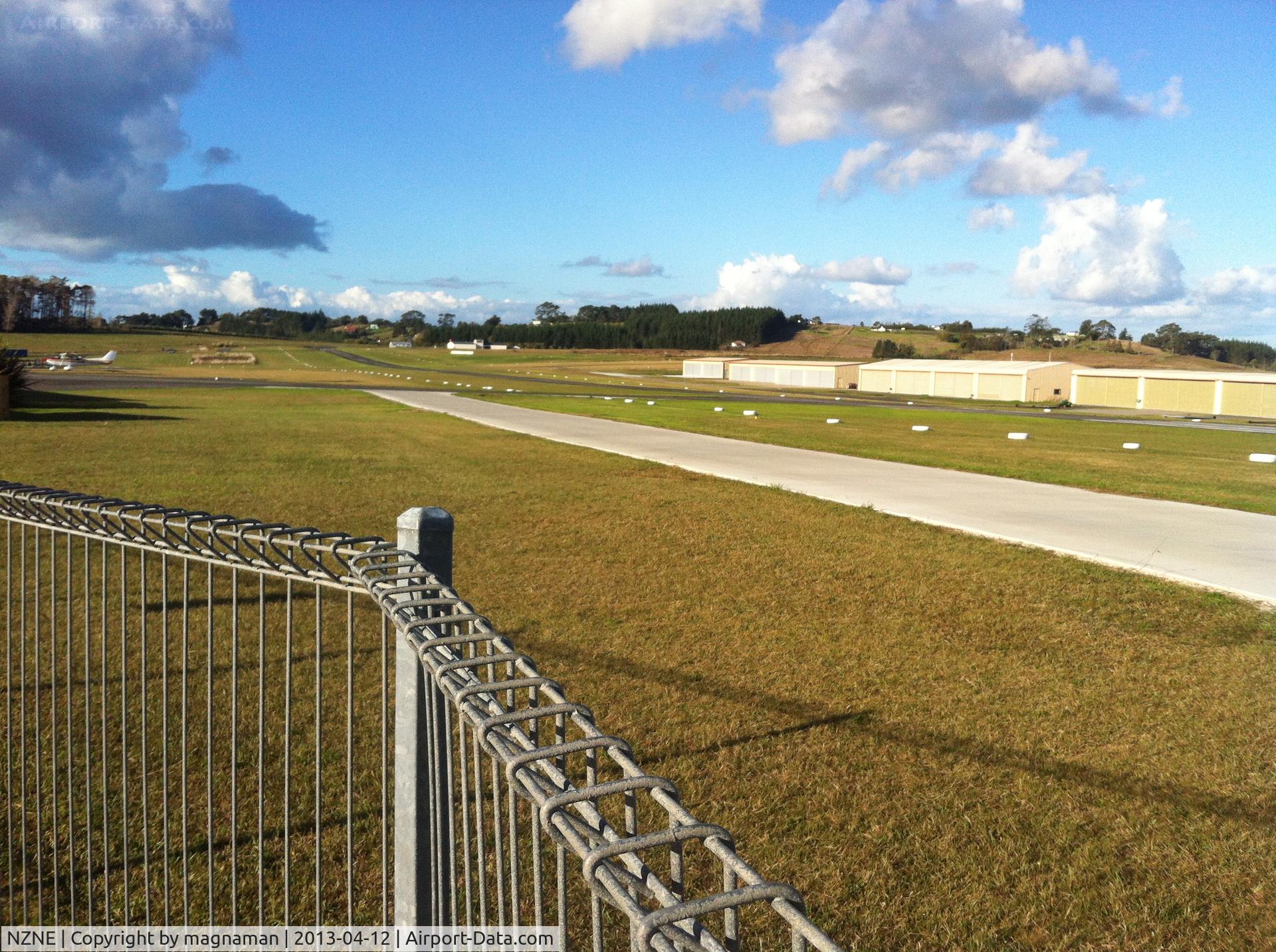 North Shore Aerodrome Airport, Auckland New Zealand (NZNE) - View from public car park down runway. Private hangars on far side.