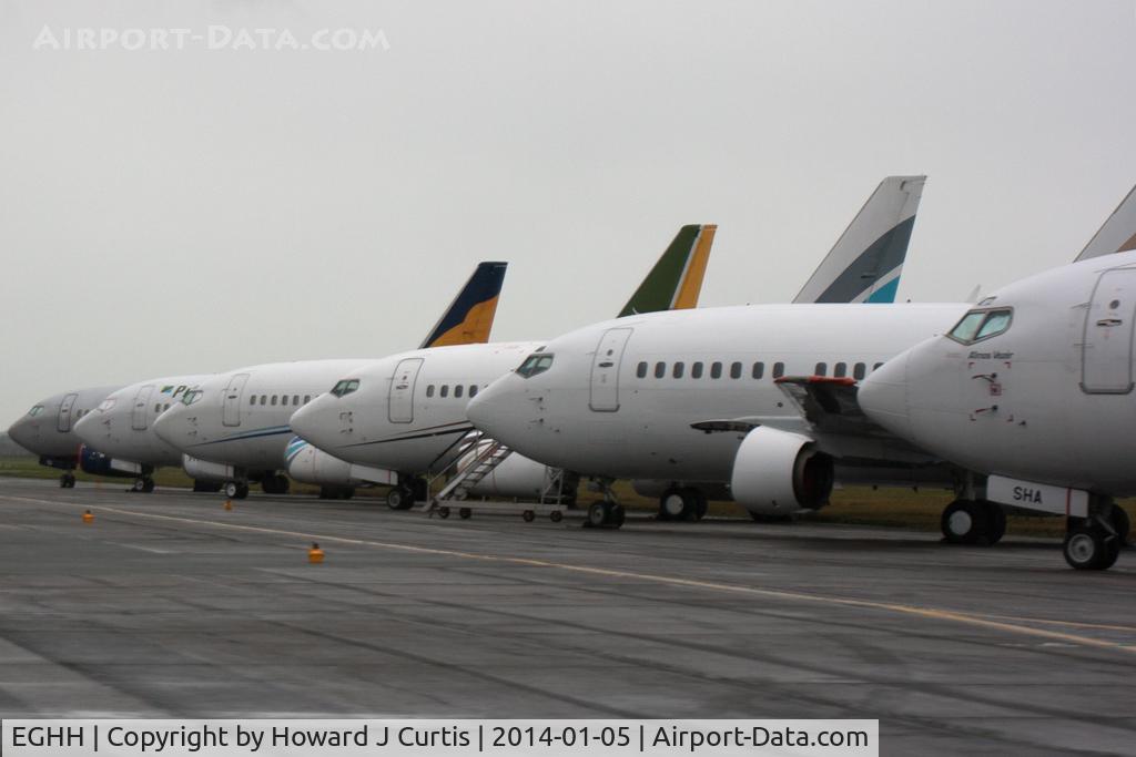 Bournemouth Airport, Bournemouth, England United Kingdom (EGHH) - A line up of six Boeing 737s parked on the former runway 35/17. Access here is not normally possible but recent flooding meant that cars were escorted across to reach the NE side of the airport.