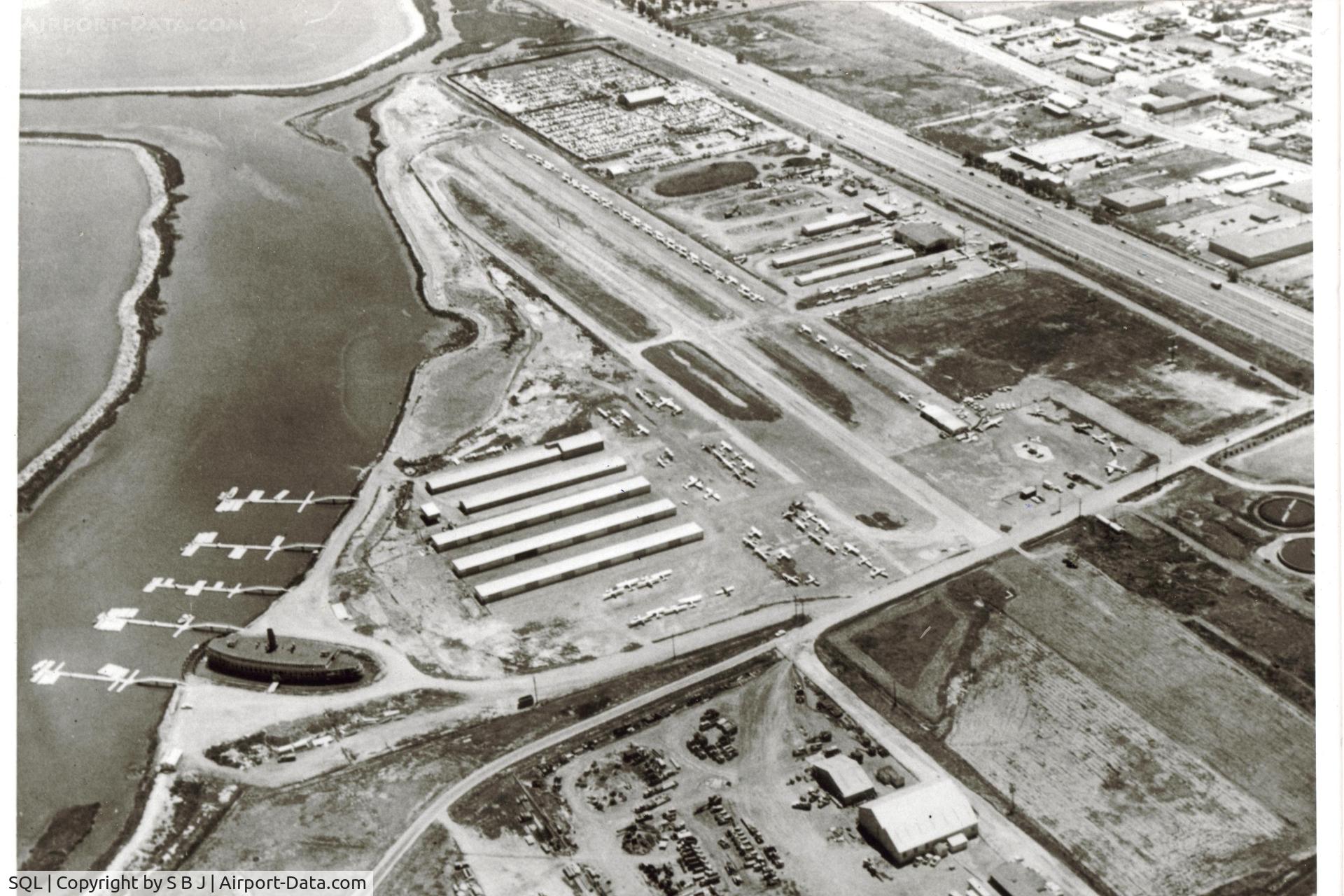 San Carlos Airport (SQL) -  1960-61 small building(2 cars in front)near the beginning of runway 12, was the airport office.Harpers Ferry was to be offices,restaurant and marina but never finished. Hap Harper was the FBO/Cessna dealer(big hangar near freeway).View is to the south. 