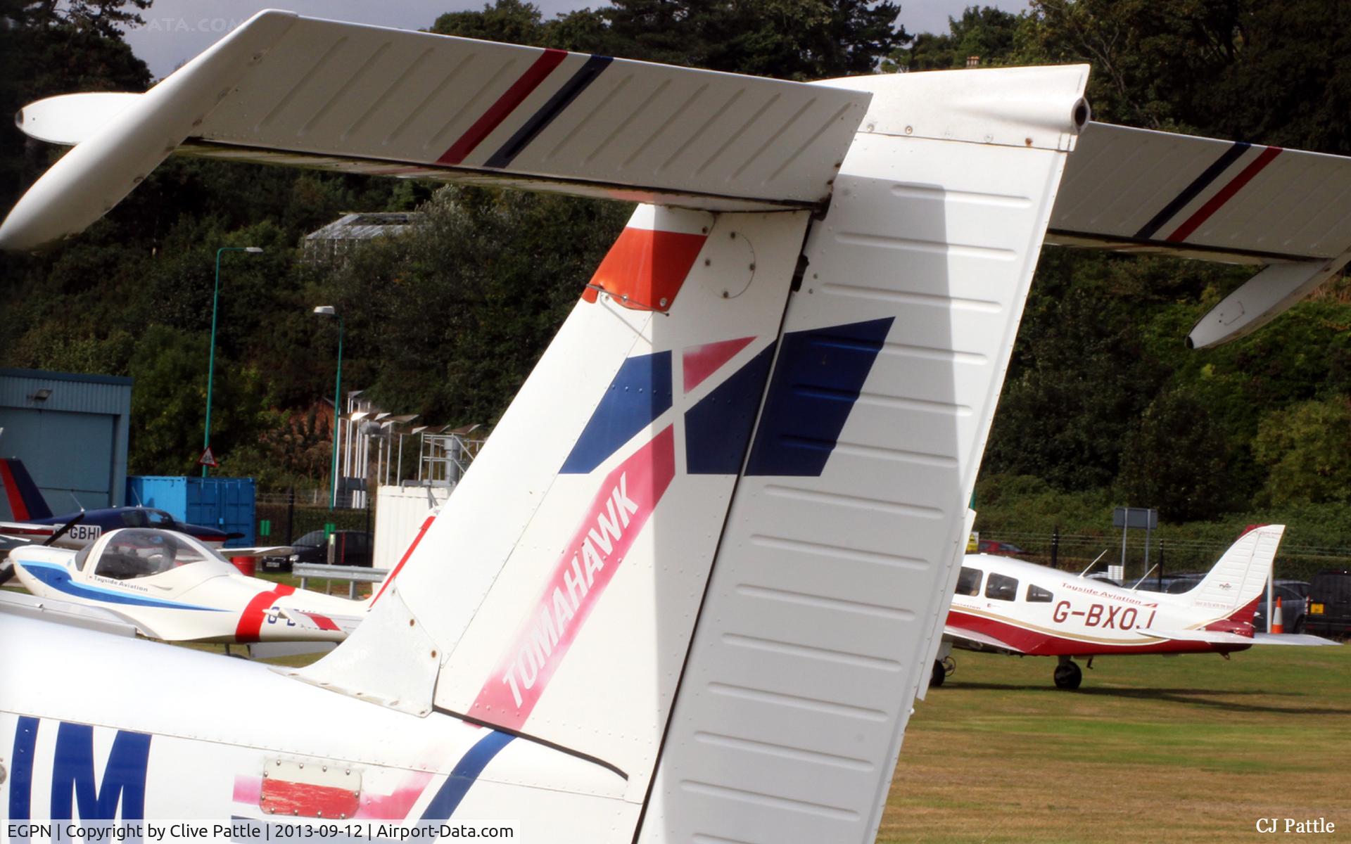 Dundee Airport, Dundee, Scotland United Kingdom (EGPN) - The GA parking area viewed through the tail of a dead Tomahawk in the airport graveyard.