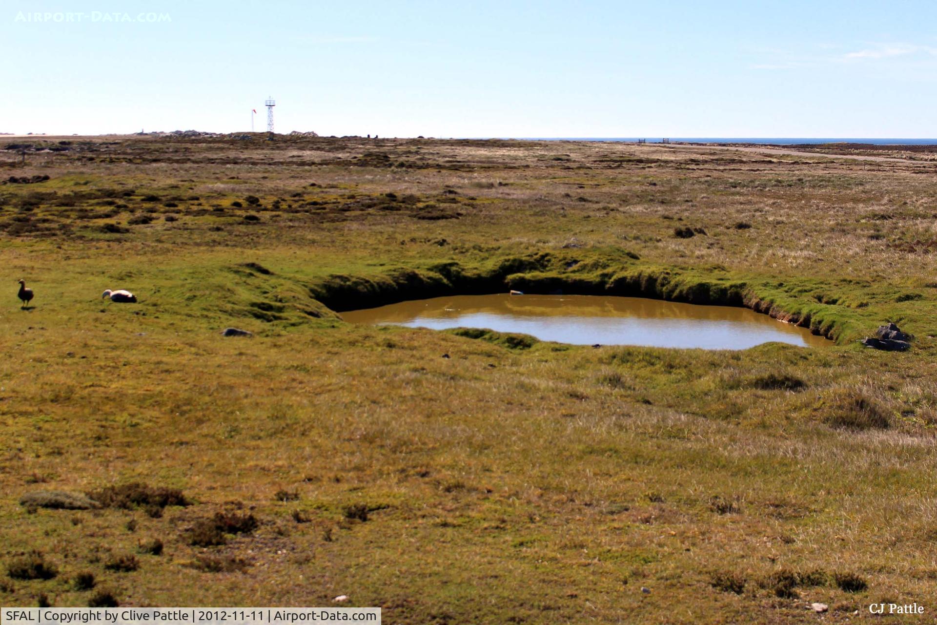 SFAL Airport - What appears to be a puddle on the southwest of Port Stanley airport is in fact a bomb crater souvenir from the Black Buck Vulcan Raids of May 1982.