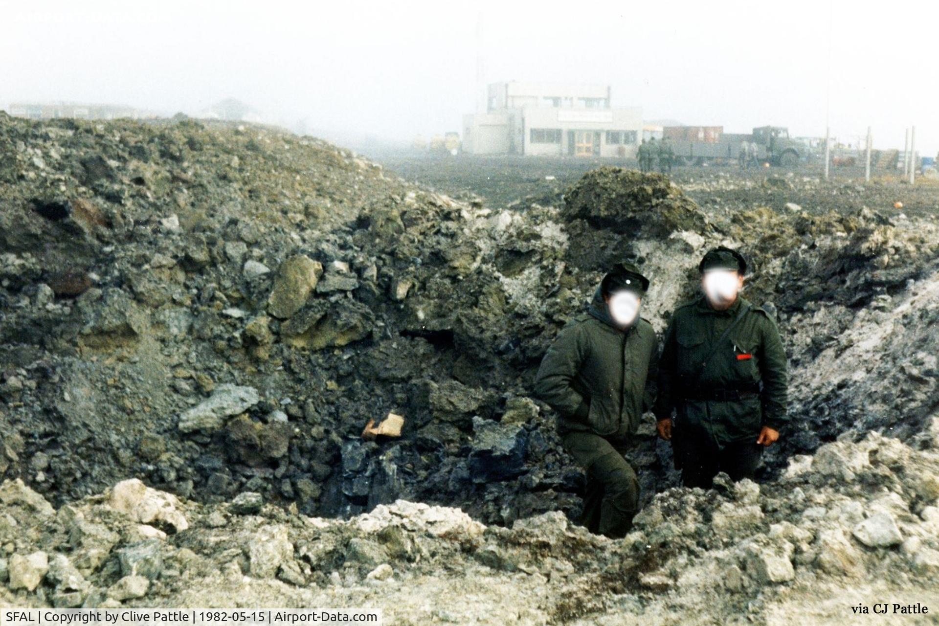 SFAL Airport - SFAL after the first Vulcan 'Black Buck' raid. Two Argentinian Officers pose in a bomb crater. The terminal is in the rear. The lorry pictured is parked on what is now the airport car park, with the yellow doors the main terminal entrance.