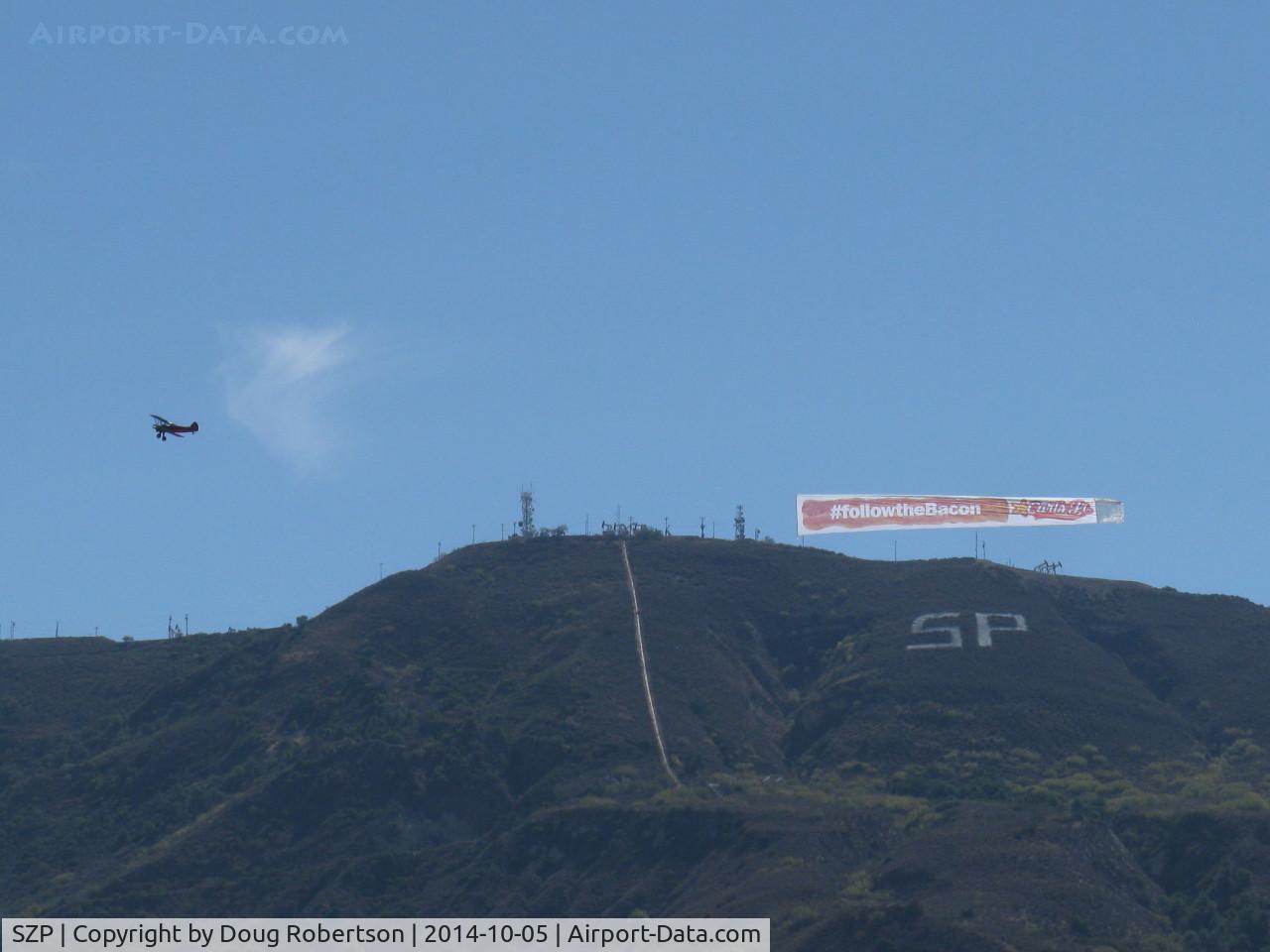 Santa Paula Airport (SZP) - N65124 Boeing Stearman towing FOLLOW THE BACON-Carl's Jr. advertising banner past South Mountain, viewable by all of Santa Paula, CA.
