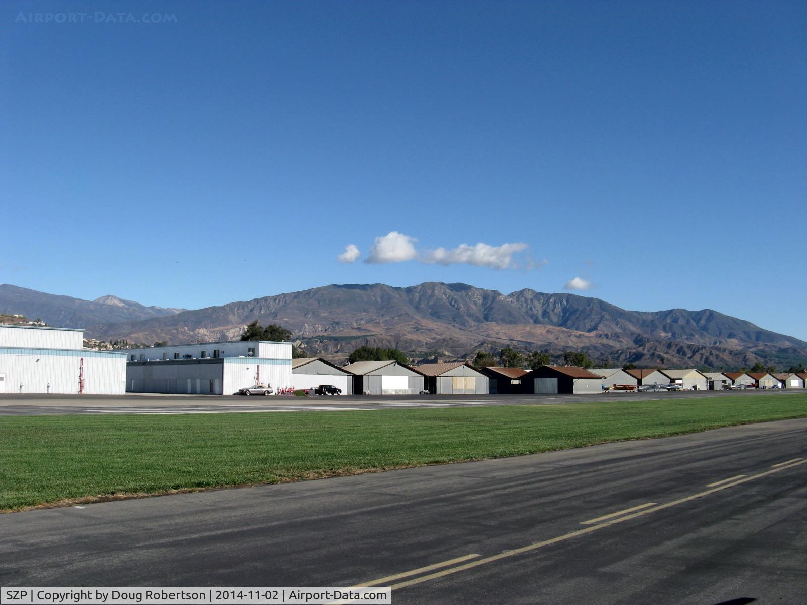 Santa Paula Airport (SZP) - Newer and older hangars. Santa Paula Peak at 4,957' in center right background. Hines Peak at 6,704' of Topa Topa Mountains beyond saddle barely shows near left side.