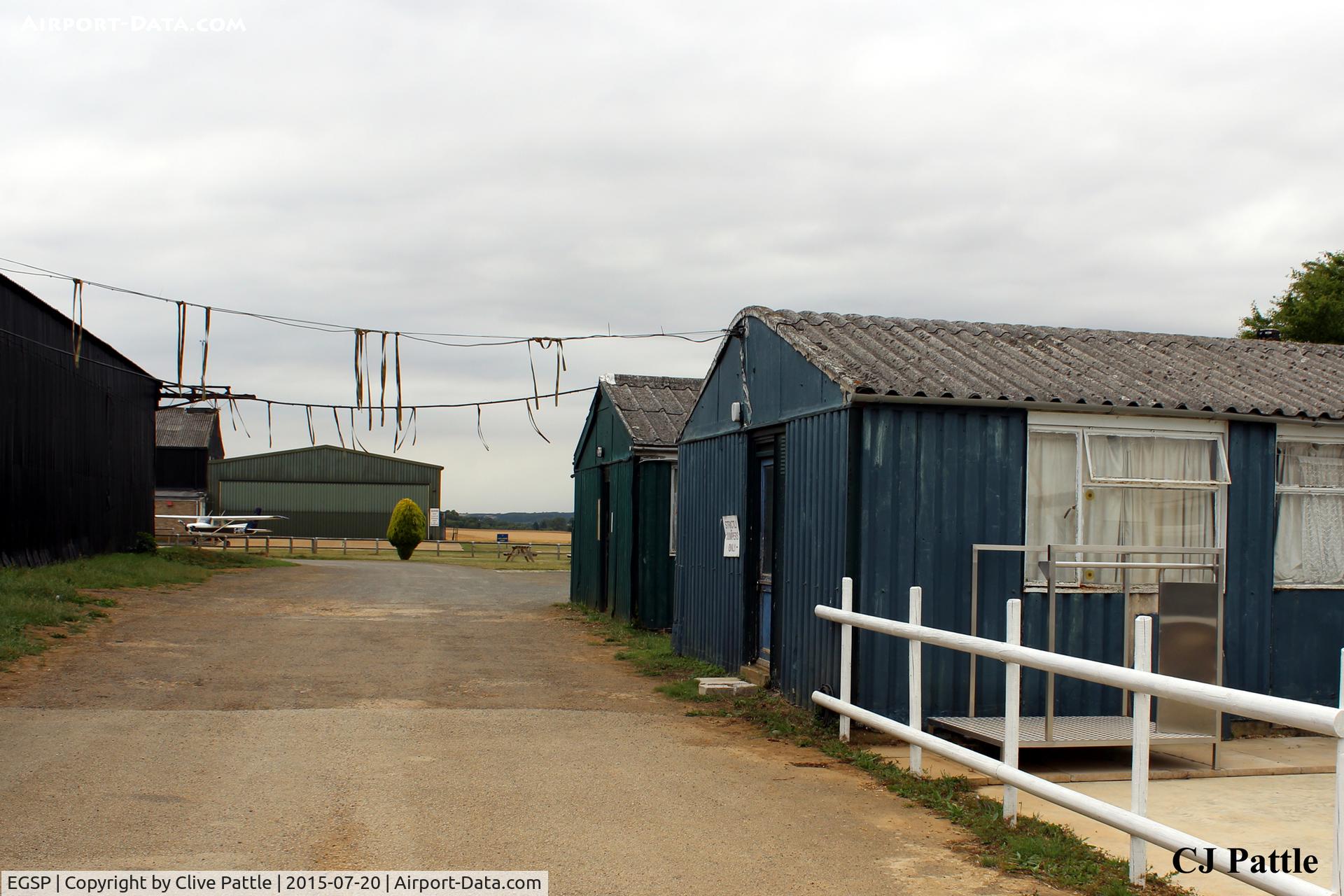Peterborough/Sibson Airport, Peterborough, England United Kingdom (EGSP) - Some of the WWII buildings still remain and are in good use at Sibson EGSP. The dangling strings are the laces of old training shoes previously thrown over the wires.