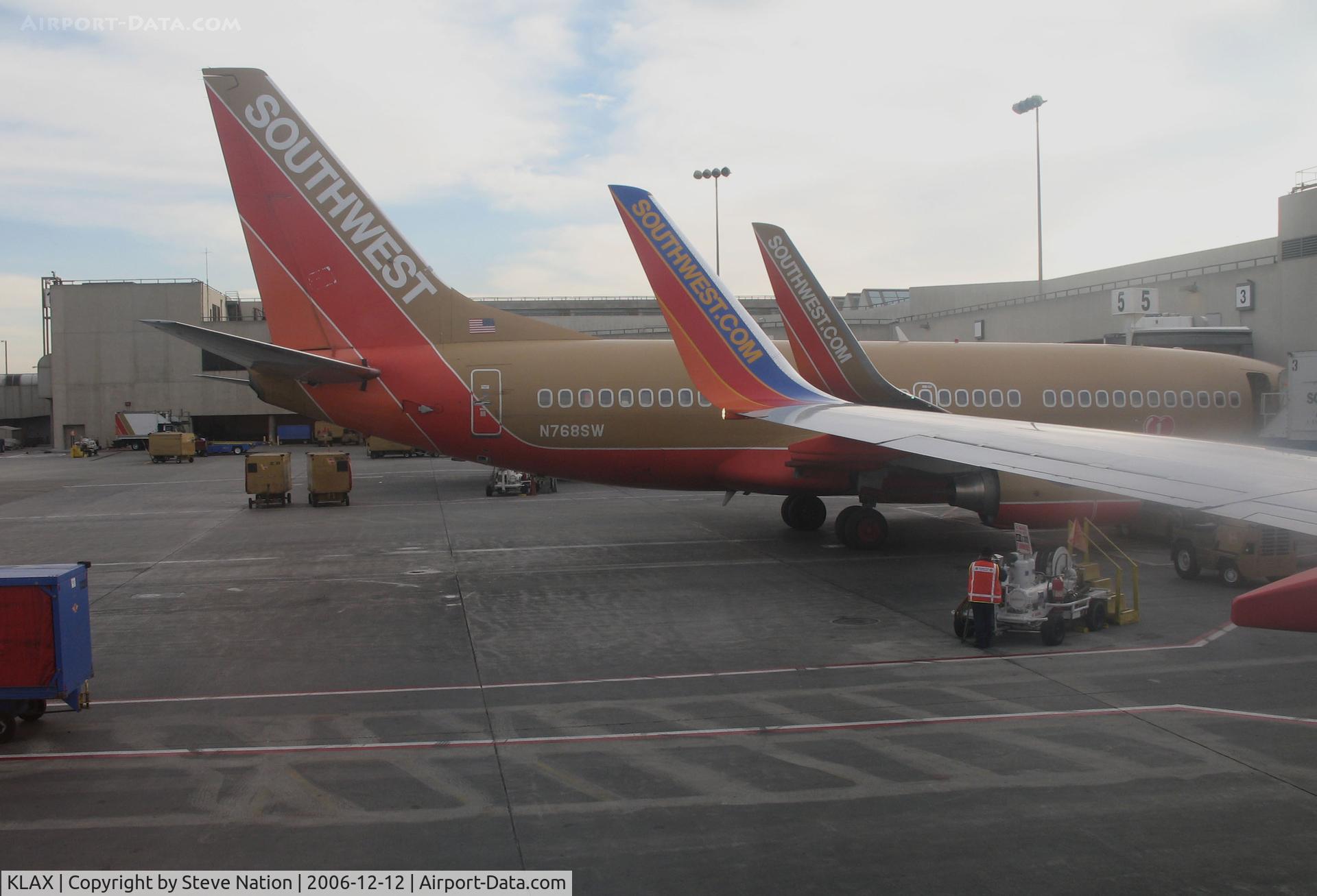 Los Angeles International Airport (LAX) - SOUTHWEST 737-7H4 N768SW and wing of sister ship at Terminal 1 - N768SW in old colors, sister ship in new colors and both with winglets
