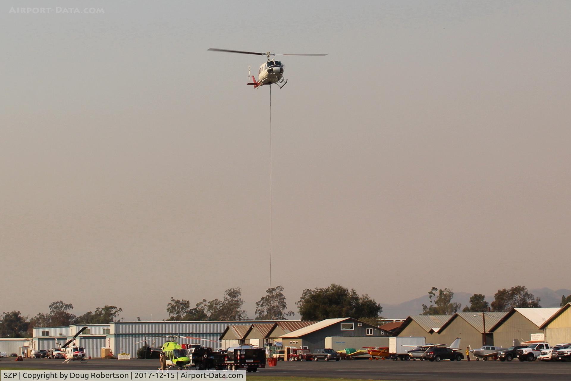 Santa Paula Airport (SZP) - Firebomber hovering over SZP FireBase with emptied sling load for replenishment. Fast turn-around time as Thomas fire here still burning (on shot date) just adjacent northern Santa Paula. Note smoky sky.