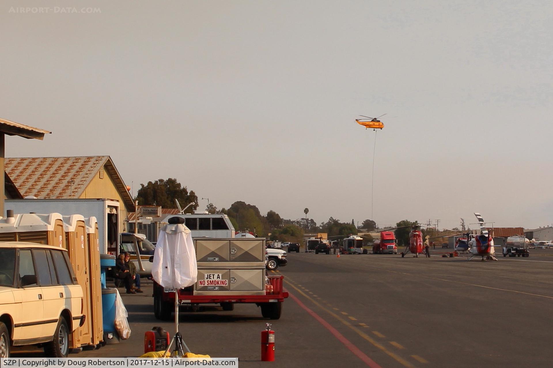 Santa Paula Airport (SZP) - CROMAN helicopter on departure to the Thomas Fire from SZP FireBase. Note PHOS-CHEK sling load and smoky sky.