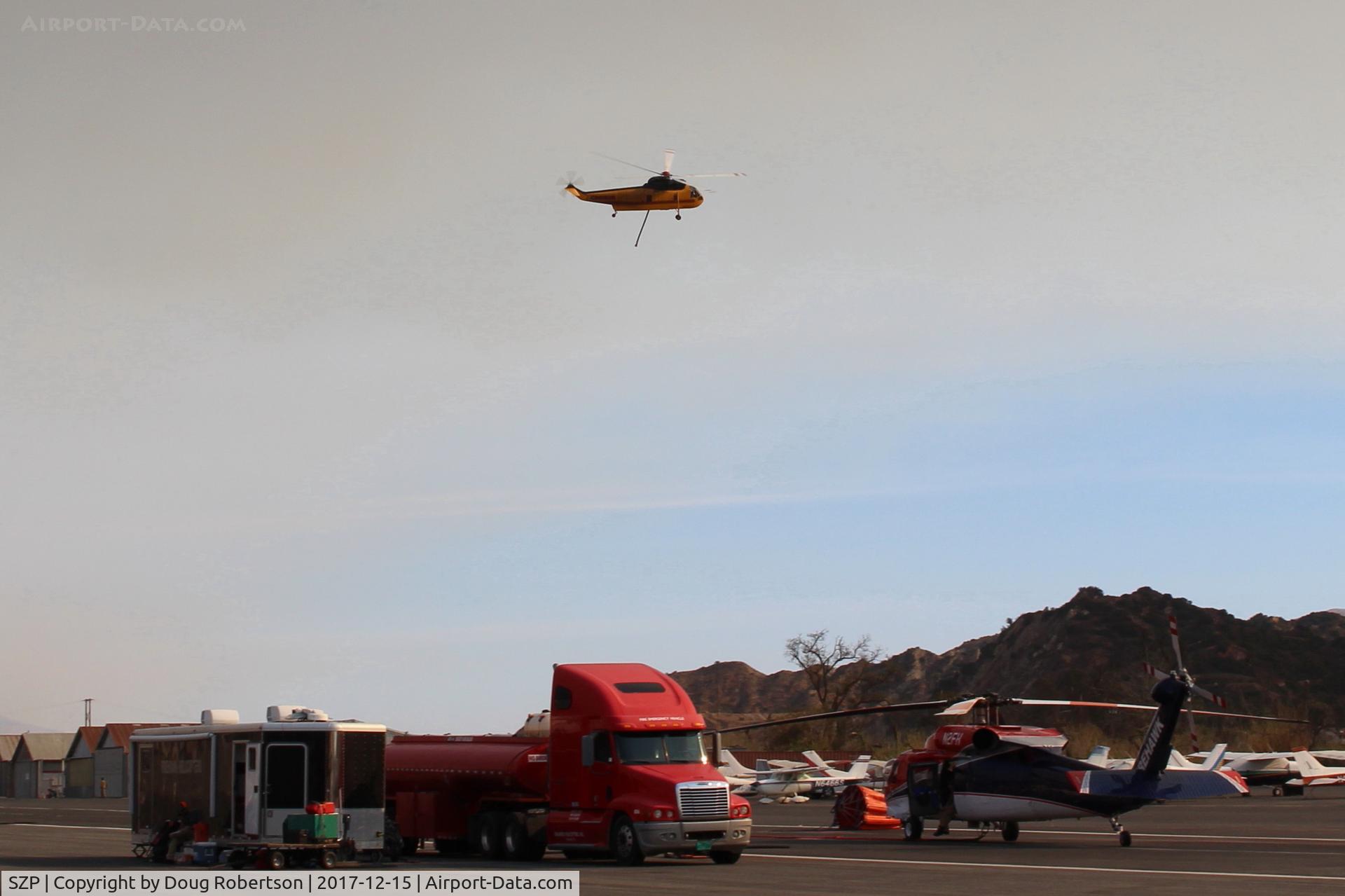 Santa Paula Airport (SZP) - CROMAN helicopter with Phos-Chek sling load dumped, returning to SZP Firebase. Note smoky sky.