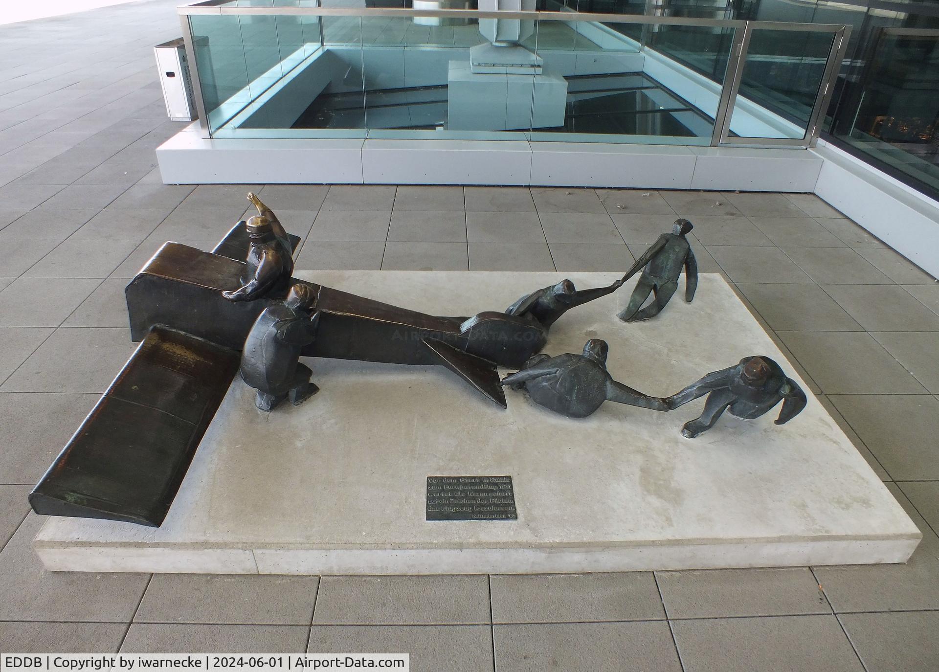 Berlin Brandenburg International Airport, Berlin Germany (EDDB) - sculpture 'Vor dem Start in Calais zum Europarundflug 1911 wartet die Mannschaft auf ein Zeichen des Piloten, das Flugzeug loszulassen' (at the take off in Calais 1911 the crew awaits a signal of the pilot to let go) 1983 by K. Biederbick at BER airport