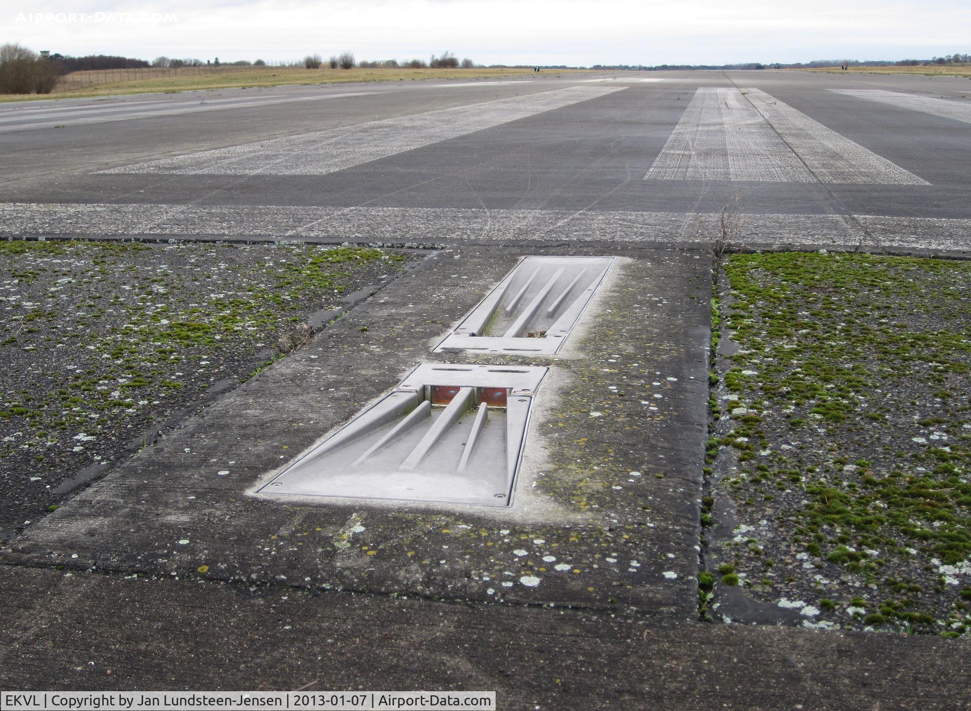 EKVL Airport - One of the Runway 28 Threshold Lights at the closed Vaerloese Air Base in Denmark. The light lenses look reddish in the photo, but the light fixture emitted green light when turned on. Adjacent Runway End Light emitted red light in opposite direction.